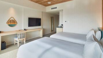 A hotel room with two beds, a desk, a chair, a TV, and a mirror.