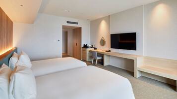 Habitación de hotel con dos camas, un escritorio, una silla, un televisor y una kitchenette pequeña.