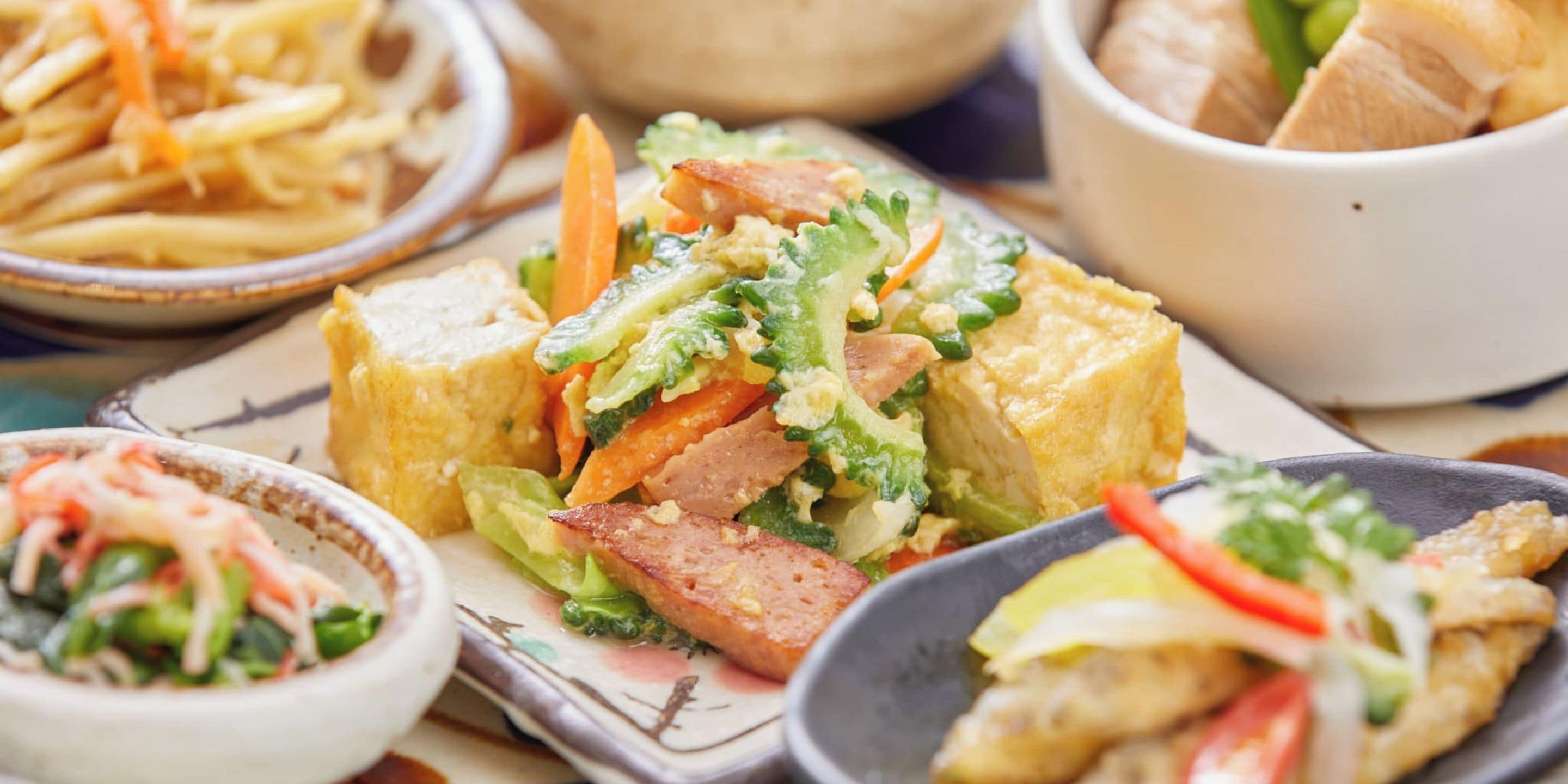 A variety of dishes including a salad with vegetables and meat, a bowl of soup, and a plate of French fries.