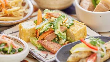 A variety of dishes including a salad with vegetables and meat, a bowl of soup, and a plate of French fries.