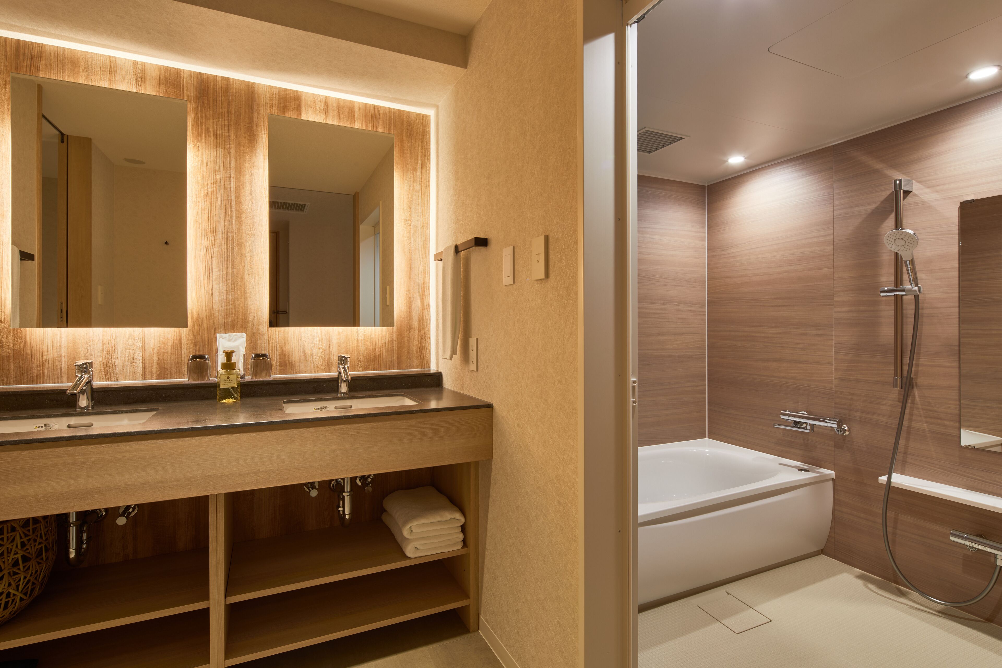 A modern bathroom with a wooden vanity, a large mirror, a bathtub, and a shower.