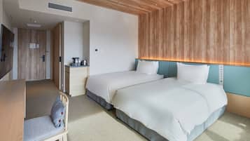 A hotel room with two beds, a desk, a chair, and a kitchenette.