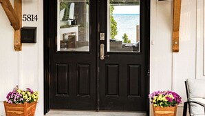 A black double door with a view of the sea, a wooden mailbox, and two flower planters. - The Carriage House on Lake Superior  I  Lakeshore & Views  I  by Relax Open Air (Duluth)