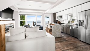 A modern kitchen with stainless steel appliances, a dining area with a view, and a cozy seating area with a sofa and cushions. - The Carriage House on Lake Superior  I  Lakeshore & Views  I  by Relax Open Air (Duluth)