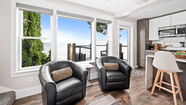A modern kitchen with a large island, white cabinetry, and a view of the outdoors. - The Carriage House on Lake Superior  I  Lakeshore & Views  I  by Relax Open Air (Duluth)