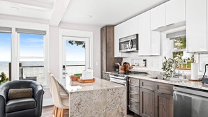 A modern kitchen with a large island, stainless steel appliances, and a view of the ocean. - The Carriage House on Lake Superior  I  Lakeshore & Views  I  by Relax Open Air (Duluth)