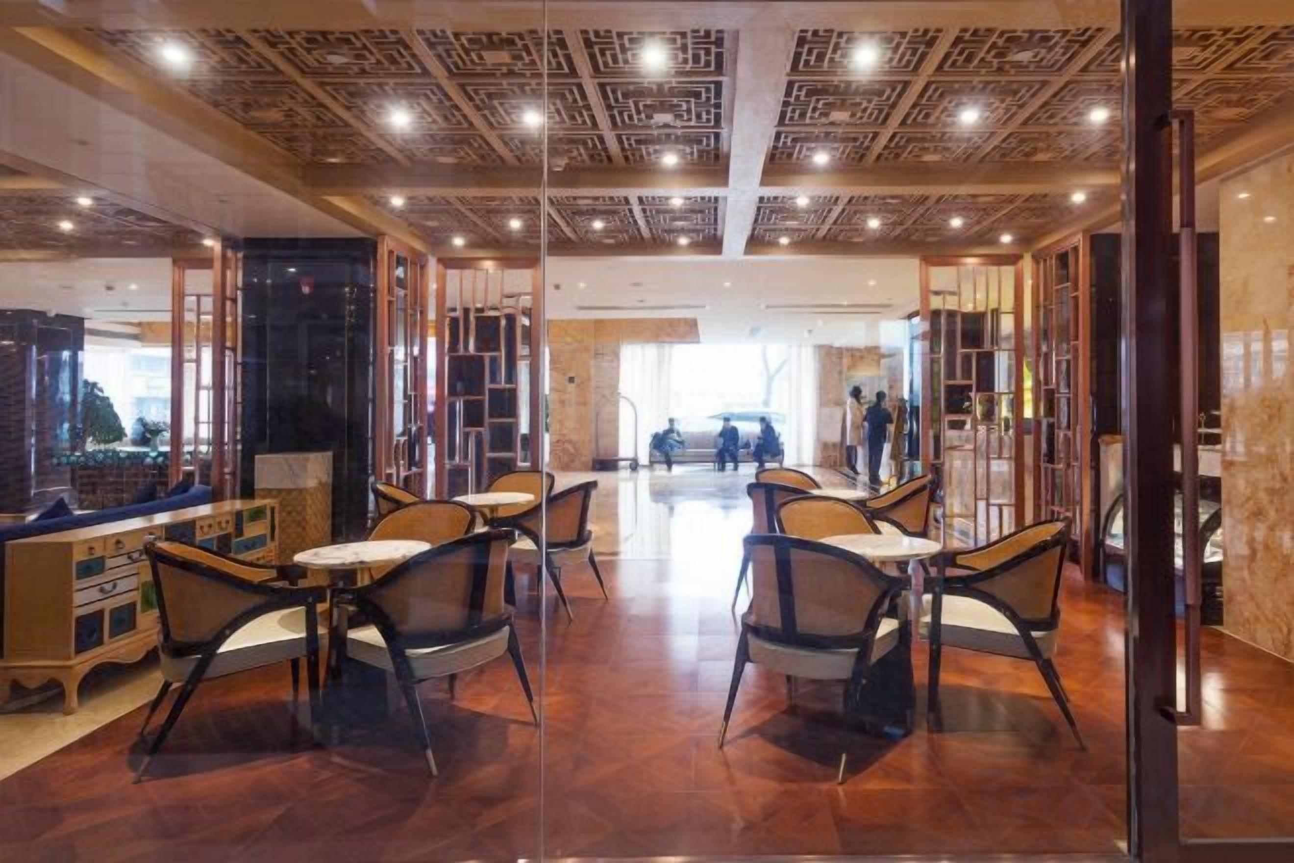 A spacious indoor area with tables and chairs, a patterned ceiling, and a view of the outdoors.