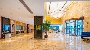 A spacious lobby with a marble floor, a chandelier, and a reception desk.