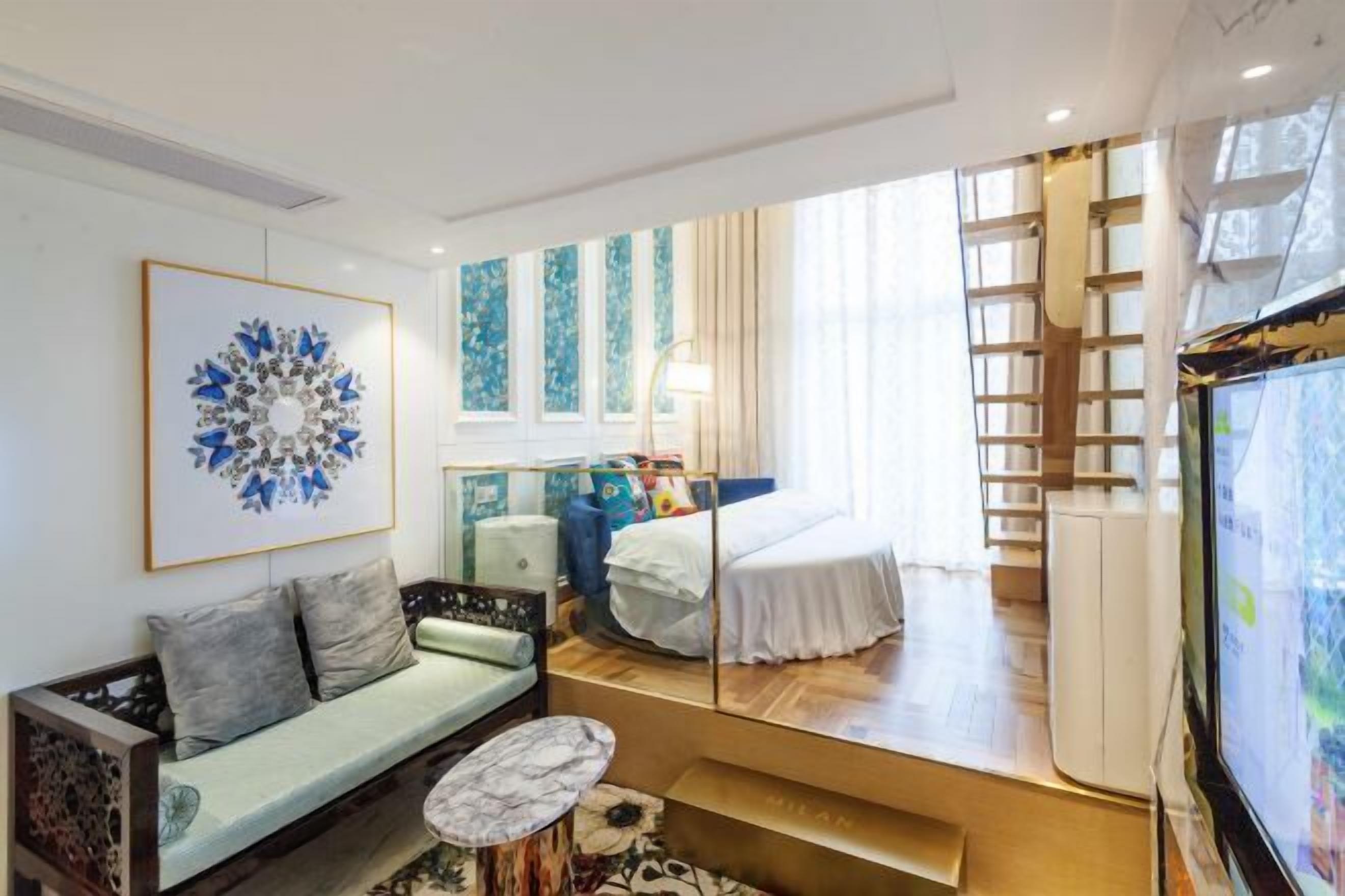 Una sala de estar moderna con un sofá, una mesa de centro, una cama, un televisor y un amplio ventanal.