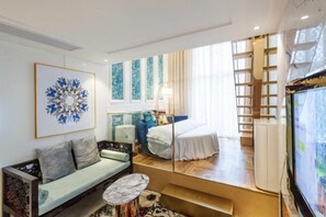Una sala de estar moderna con un sofá, una mesa de centro, una cama, un televisor y un amplio ventanal.