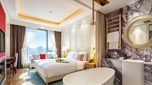 A hotel room with a large bed, a bathtub, a desk, and a city view.