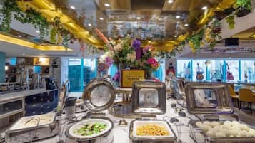 A buffet area with various food containers and a decorative floral arrangement.