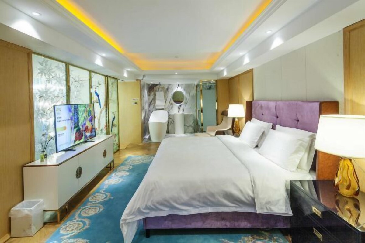 A hotel room with a bed, a TV, a bathroom, and a desk.