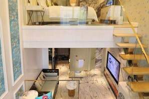Habitación de hotel moderna con balcón acristalado, suelo de mármol, televisor y escalera.