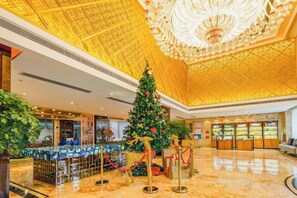 Un vestíbulo con un gran árbol de Navidad, un mostrador de recepción y un candelabro.