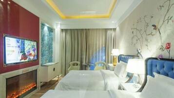 A hotel room with a bed, a TV, a fireplace, and a window with curtains.