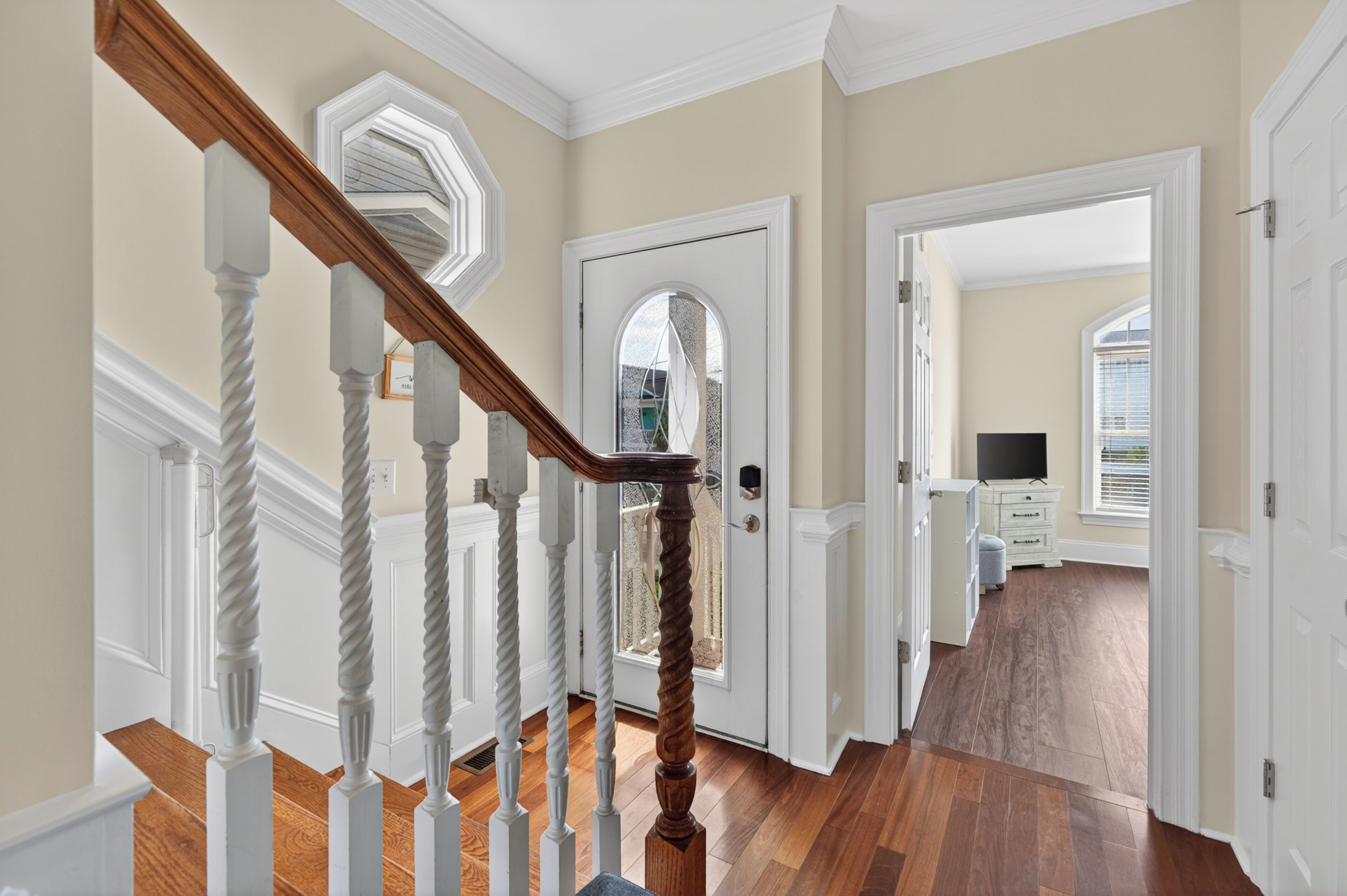 A staircase with white balusters and a wooden handrail leading to a door with a glass panel.