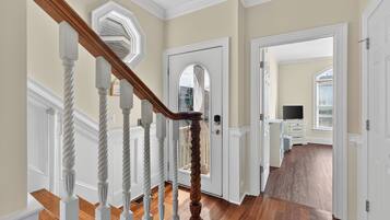A staircase with white balusters and a wooden handrail leading to a door with a glass panel.