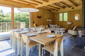 A wooden interior with a dining table set for six, a sofa, and a fireplace. - Chalet du Gouter - 8 guests , 4 bedrooms, garden, parking (Les Praz de Chamonix)