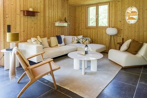 Una sala de estar acogedora con un sofá modular, una mesa de centro redonda, un sillón de madera mecedora y una lámpara de pie.