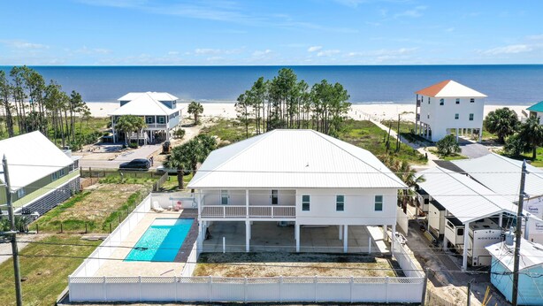 Una propiedad frente al mar con una casa grande, piscina, terraza cubierta y vista al océano.