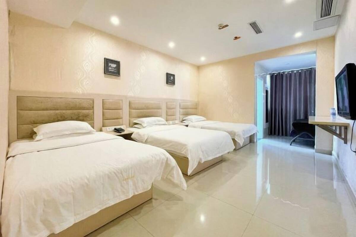 A hotel room with two beds, a television, and a bathroom visible through an open door.