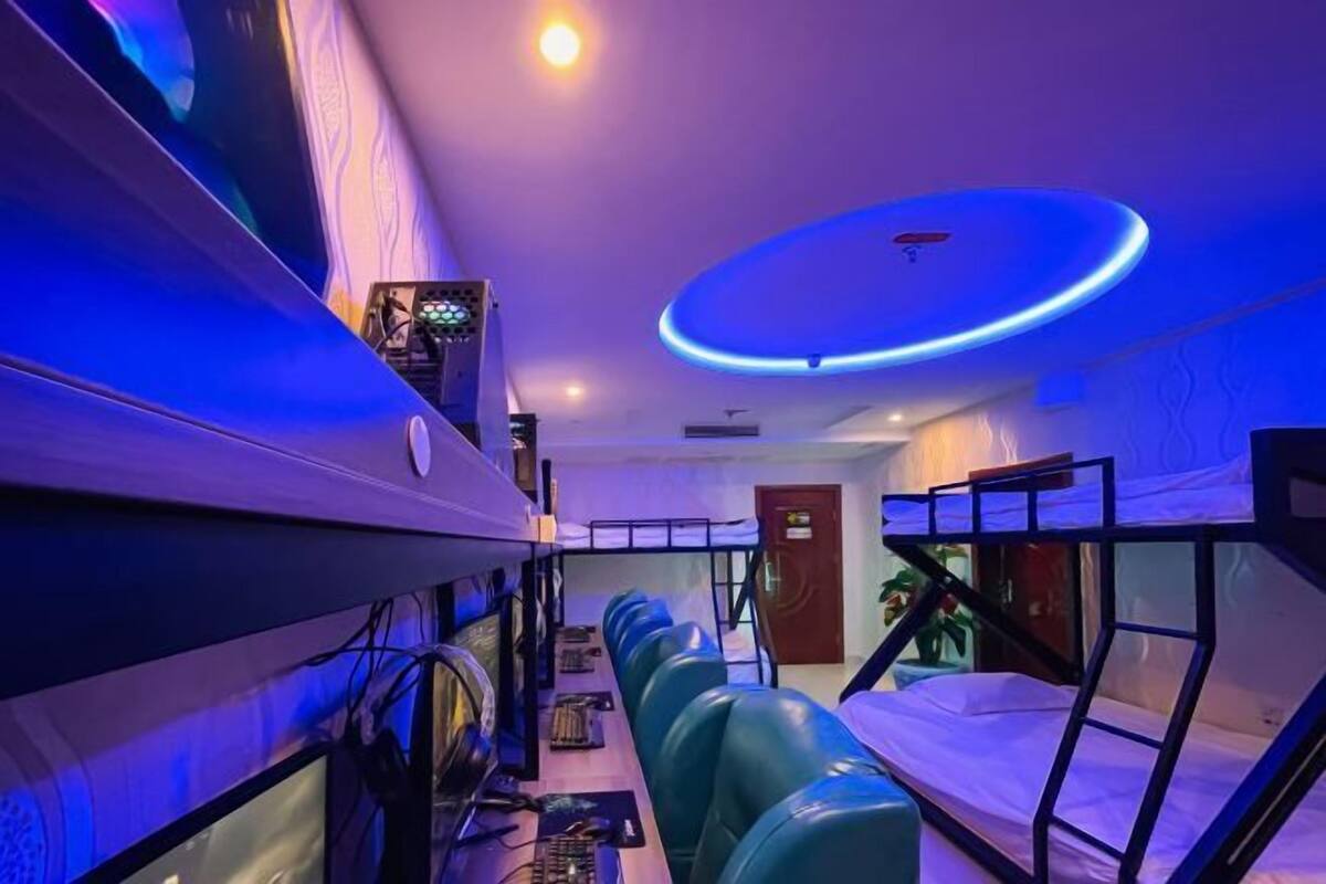 A room with bunk beds, a desk with a computer, and a circular light fixture on the ceiling.