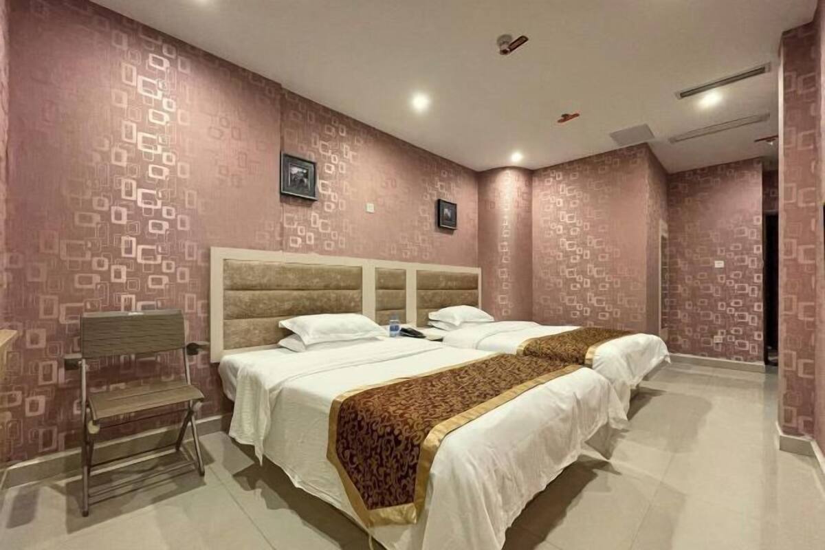 A hotel room with two beds, a desk, and a chair.