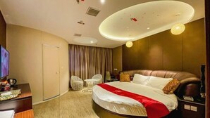 Une chambre d’hôtel avec un lit rond, une télévision, un bureau et un coin salon.