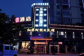 A hotel with a prominent neon sign, a large entrance, and a visible parking area. - Fuzhou Hongguoshu Holiday Hotel (Fuzhou)