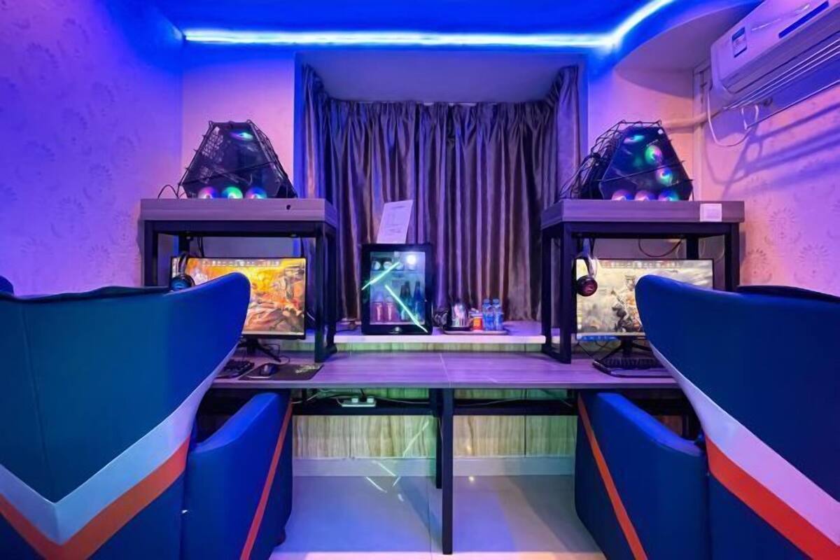 A gaming room with two monitors, a gaming chair, and a desk.