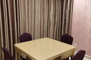 Una habitación con una mesa de madera y cuatro sillas moradas.