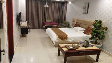 Ein Hotelzimmer mit Bett, Nachttisch, Lampe, Zimmerpflanze und Schreibtisch mit Stuhl.