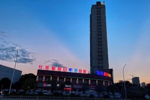 Un edificio alto con señalización iluminada, un estacionamiento y un cielo despejado.