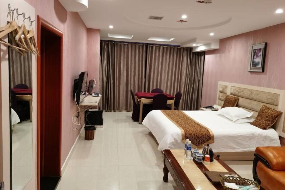 A hotel room with a bed, desk, chair, and a mirror.