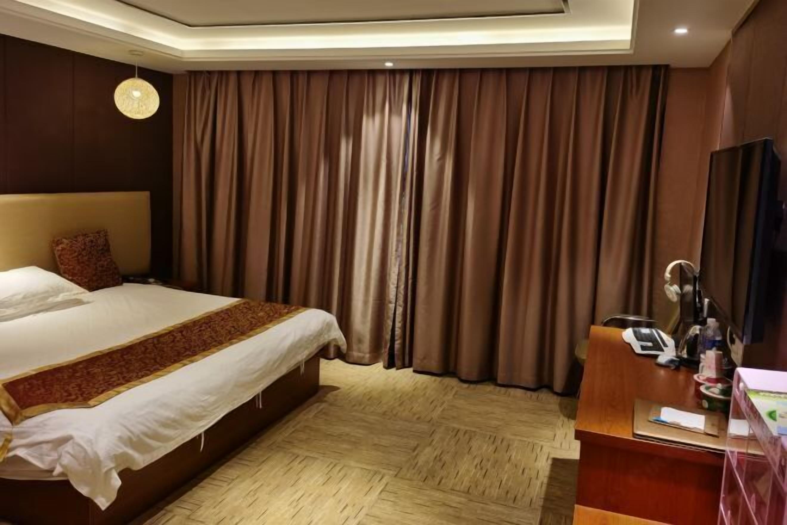 A hotel room with a large bed, a desk with a telephone, and a mirror.
