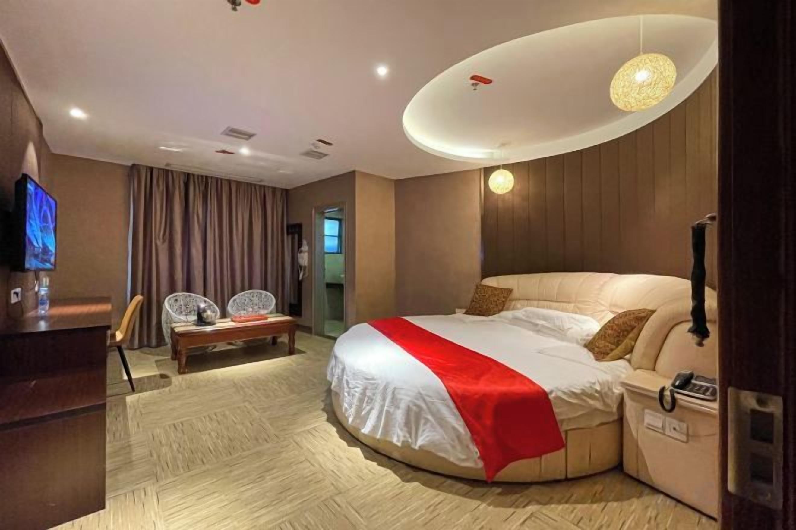 A hotel room with a bed, a desk, a chair, and a television.
