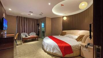 A hotel room with a bed, a desk, a chair, and a television.