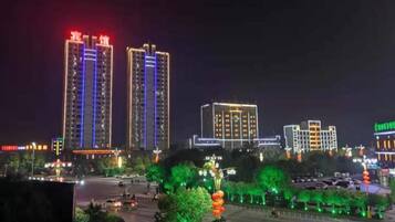 A nighttime cityscape with illuminated high-rise buildings and a well-lit street.