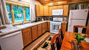 A kitchen with wooden cabinets, a stove, a microwave, and a refrigerator. - Your Sunny Bungalow Awaits! (Big Indian)