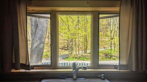 A kitchen with a large window, a sink, and a stone wall. - Your Sunny Bungalow Awaits! (Big Indian)