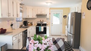 A modern kitchen with white cabinets, stainless steel appliances, and a black and white patterned rug. - Relax by Oak Bluffs Harbor, enjoy your 3-bedroom East Chip retreat (Oak Bluffs)
