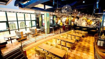 Un restaurant avec un sol à carreaux, de nombreuses tables et chaises, et une fresque murale.