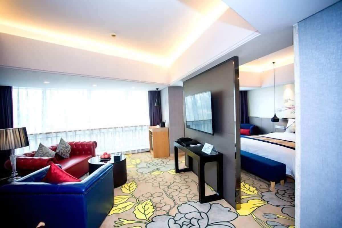 A hotel room with a sofa, a bed, a desk, and a large window.