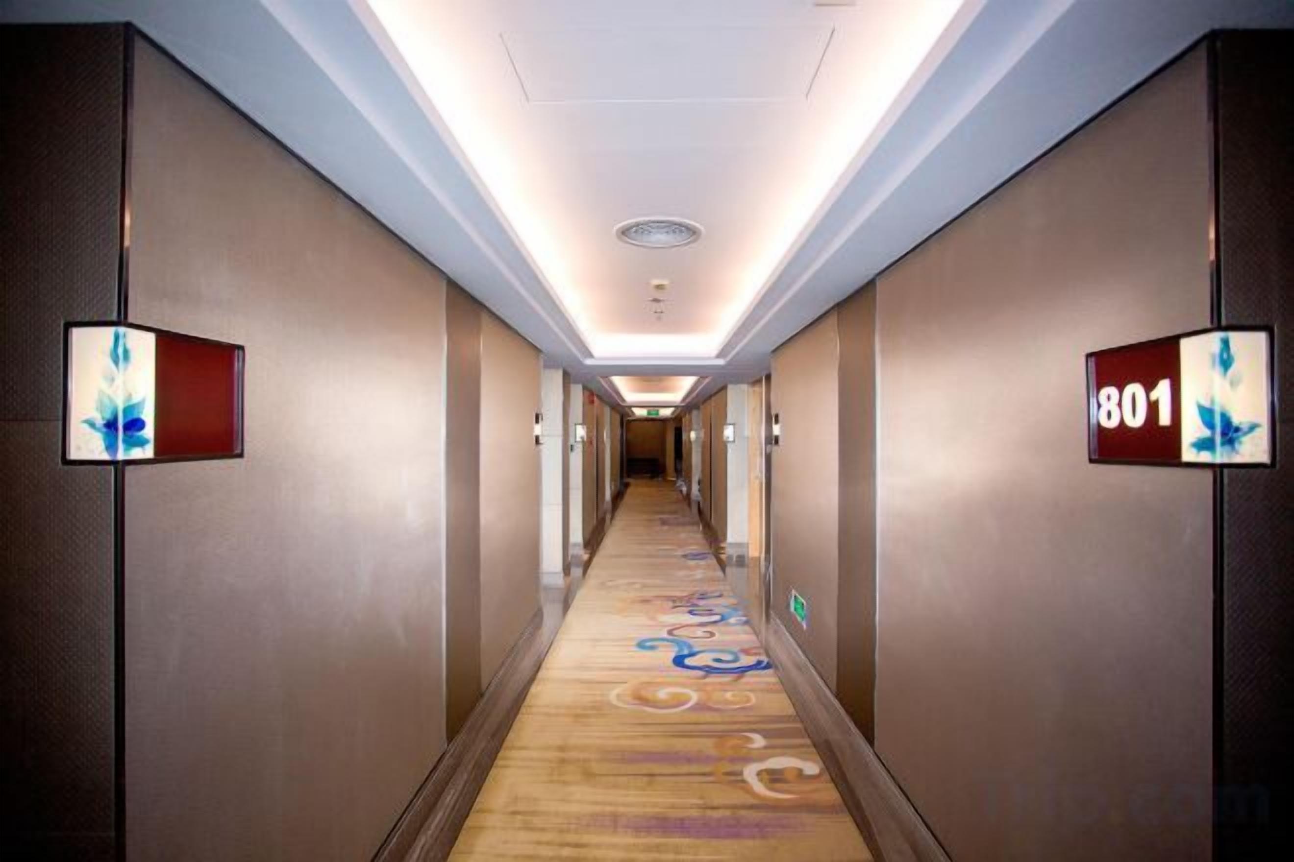 Corredor de hotel com piso revestido de carpete, luminárias fixadas na parede e placa indicando a sala 801.