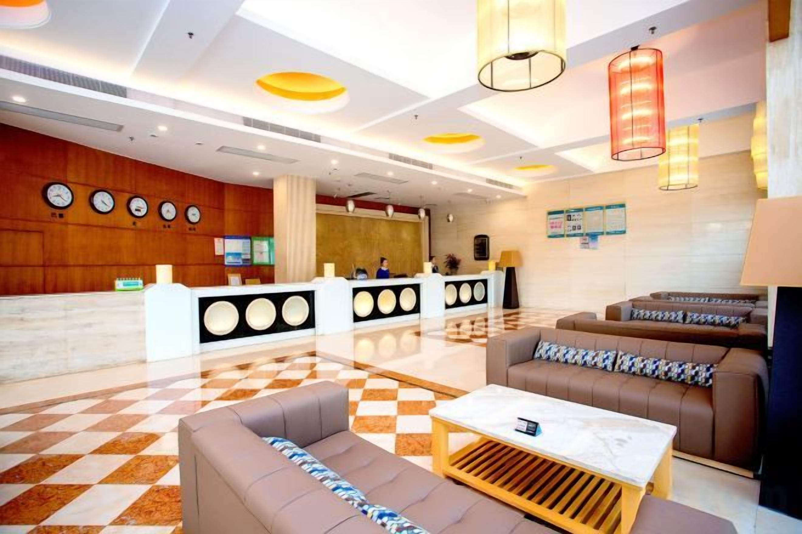 A hotel lobby with a reception desk, seating area, and a checkered floor.