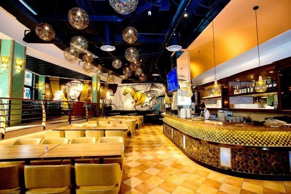 A restaurant interior with a bar area, seating arrangements, and a decorative ceiling.