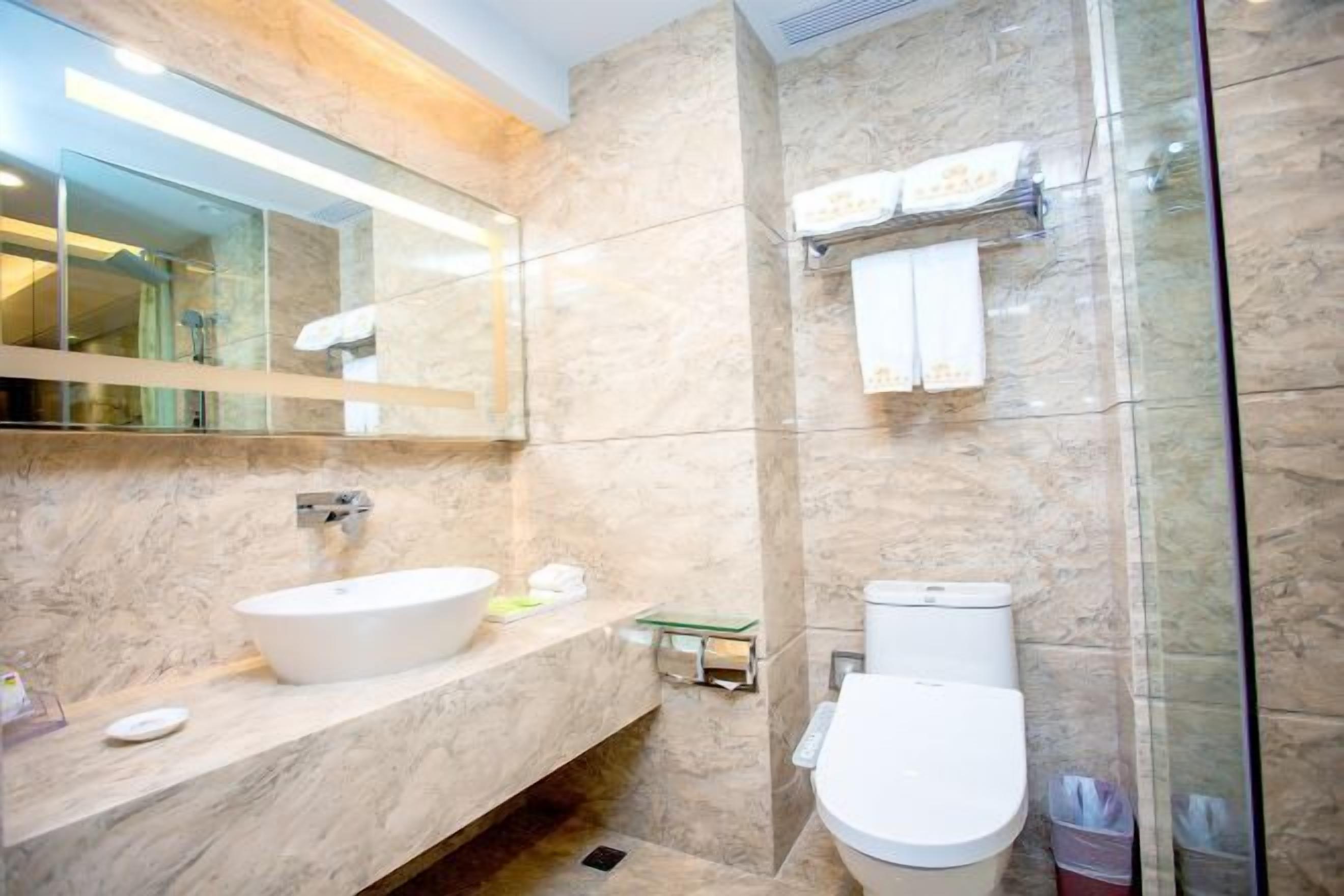 Un baño moderno con lavamanos de mármol, inodoro y cabina de ducha de vidrio.
