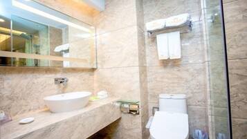 Uma casa de banho moderna com lavatório de mármore, sanita e cabine de duche em vidro.