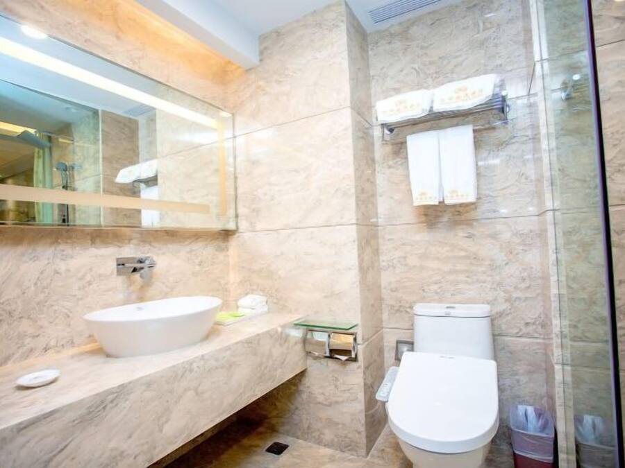 Un baño moderno con lavamanos de mármol, inodoro y cabina de ducha de vidrio.